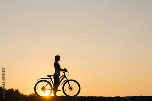 Silhouette of a woman with her bicycle on the beach. You only live once 