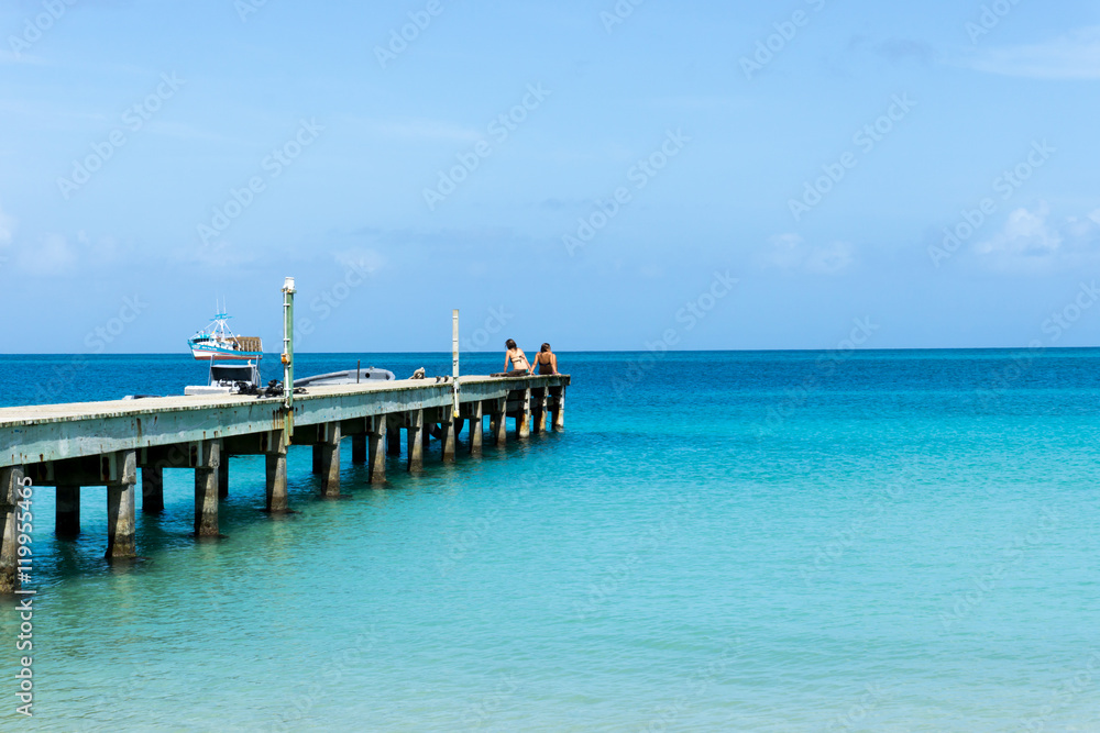 Boardwalk into the tropical sea with blue sky