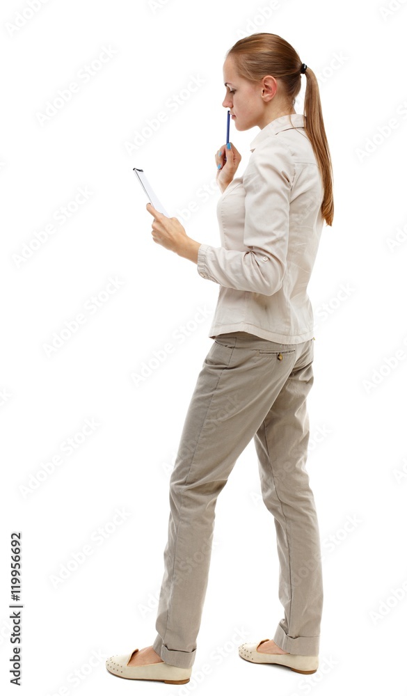 back view of stands woman takes notes in a notebook. girl watching. Isolated over white background. Skinny girl in white denim suit thoughtfully reading record back view of stands woman takes notes in a notebook. girl watching. Isolated over white background. Skinny girl in white denim suit thoughtfully reading record