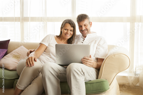 happy middle aged couple with a computer