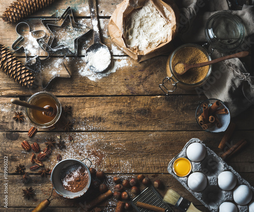 Christmas holiday cooking and baking ingredients. Cookie molds, spices, flour, eggs, cocoa powder, sugar, honey, nuts on old rustic wooden background. Top view, copy space photo