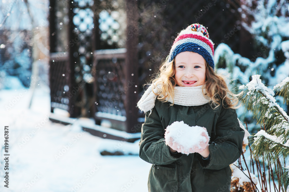 happy child girl playing with snow on snowy winter walk on backyard, making snowballs in the garden happy child girl playing with snow on snowy winter walk on backyard, making snowballs in the garden