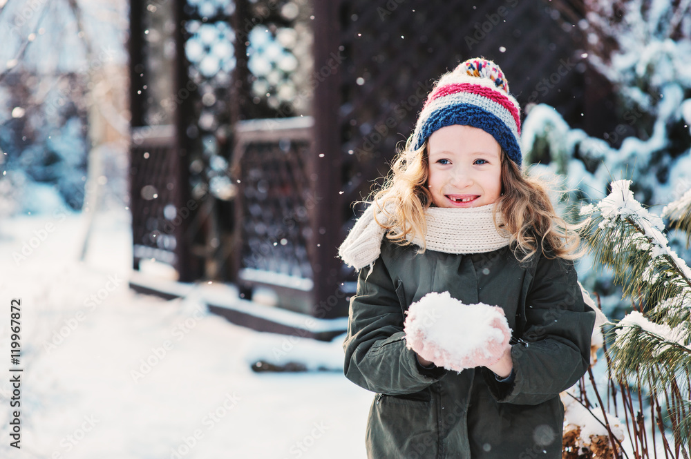 happy child girl playing with snow on snowy winter walk on backyard, making snowballs in the garden happy child girl playing with snow on snowy winter walk on backyard, making snowballs in the garden