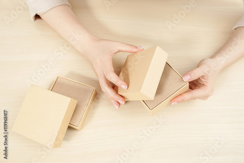Female hands opening carton box, flat lay. Top view on woman holding and unblocking package with some product, free space. Delivery service. online shopping, parcel getting concept