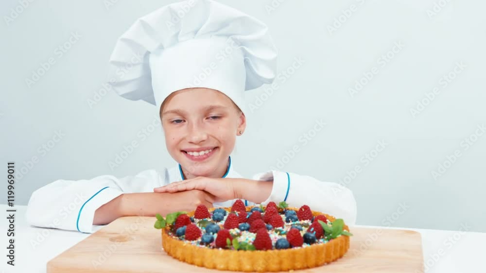 Close up portrait young baker near chocolate cake with sweets and fruits. Isolated on white Close up portrait young baker near chocolate cake with sweets and fruits. Isolated on white