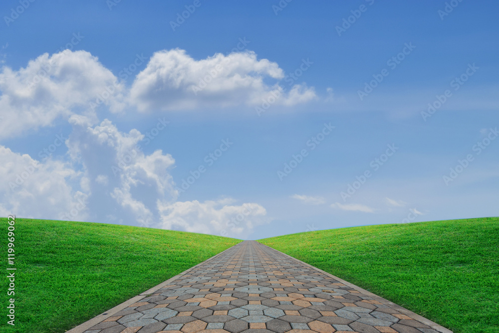 Stone walkway with green grass of hill and blue sky on the horiz Stone walkway with green grass of hill and blue sky on the horiz