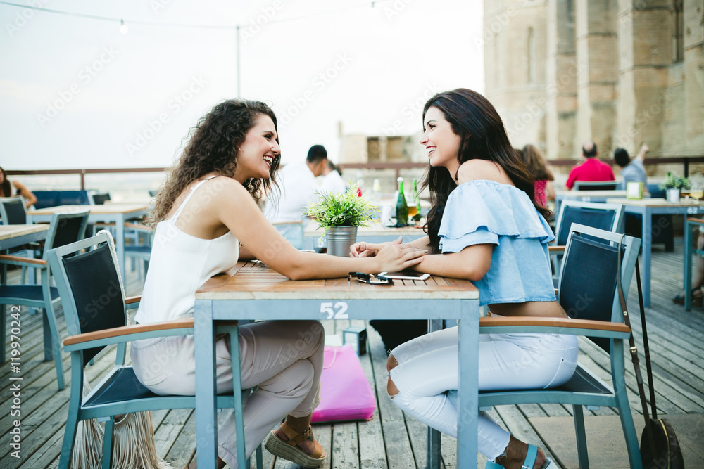 Beautiful young women talking in a restaurant terrace.