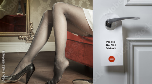Hotel door with do not disturb icon and sexy female legs on the background; adultery concept