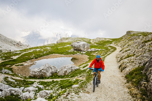 Mountain Bike cyclist riding single track on rocks healthy lifestyle active vacation in Italian Alps