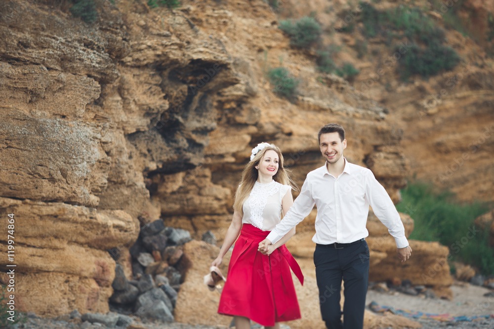 Romantic loving couple walking on the beach with rocks and stones