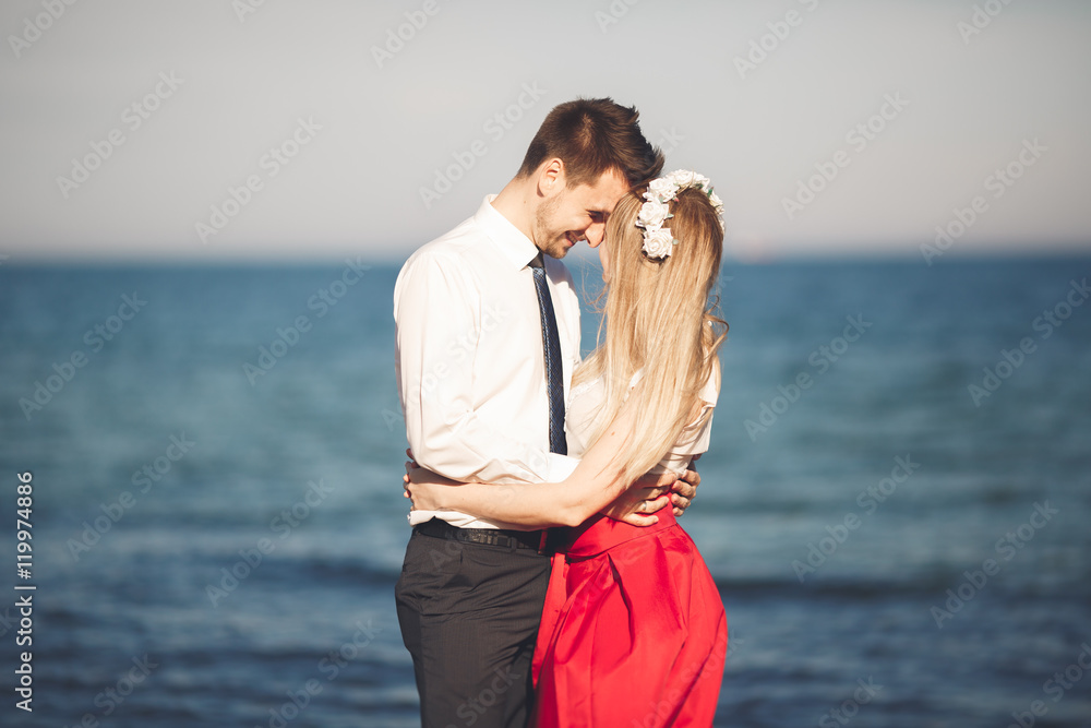 Young happy couple walking on beach smiling holding around each other. Love story Young happy couple walking on beach smiling holding around each other. Love story