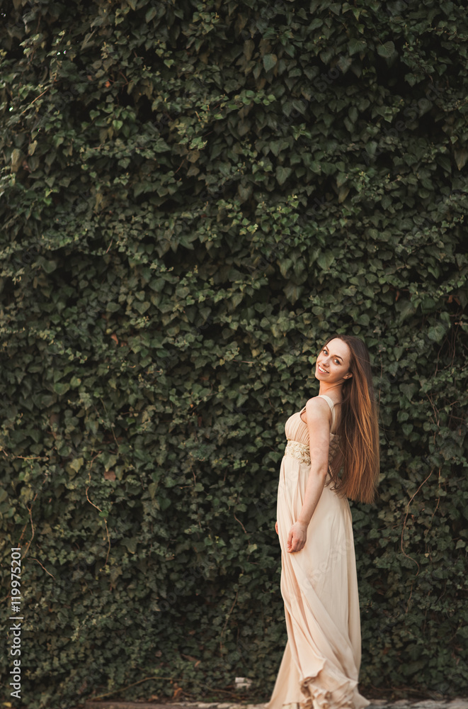 Beautiful girl, model near the wall of leaves and bushes in park Beautiful girl, model near the wall of leaves and bushes in park