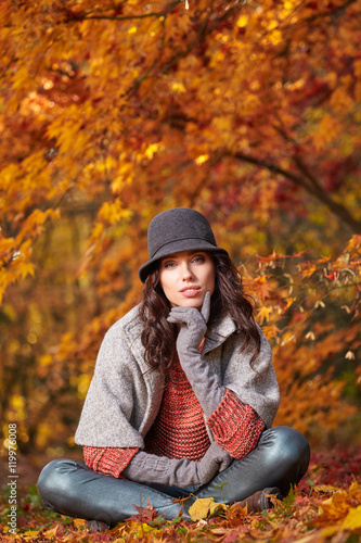 Fashionable woman and fall yellow, red maple park background.