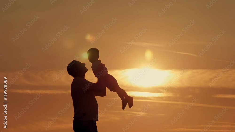 father and son silhouettes play at sunset beach. Happy family father and son silhouettes play at sunset beach. Happy family