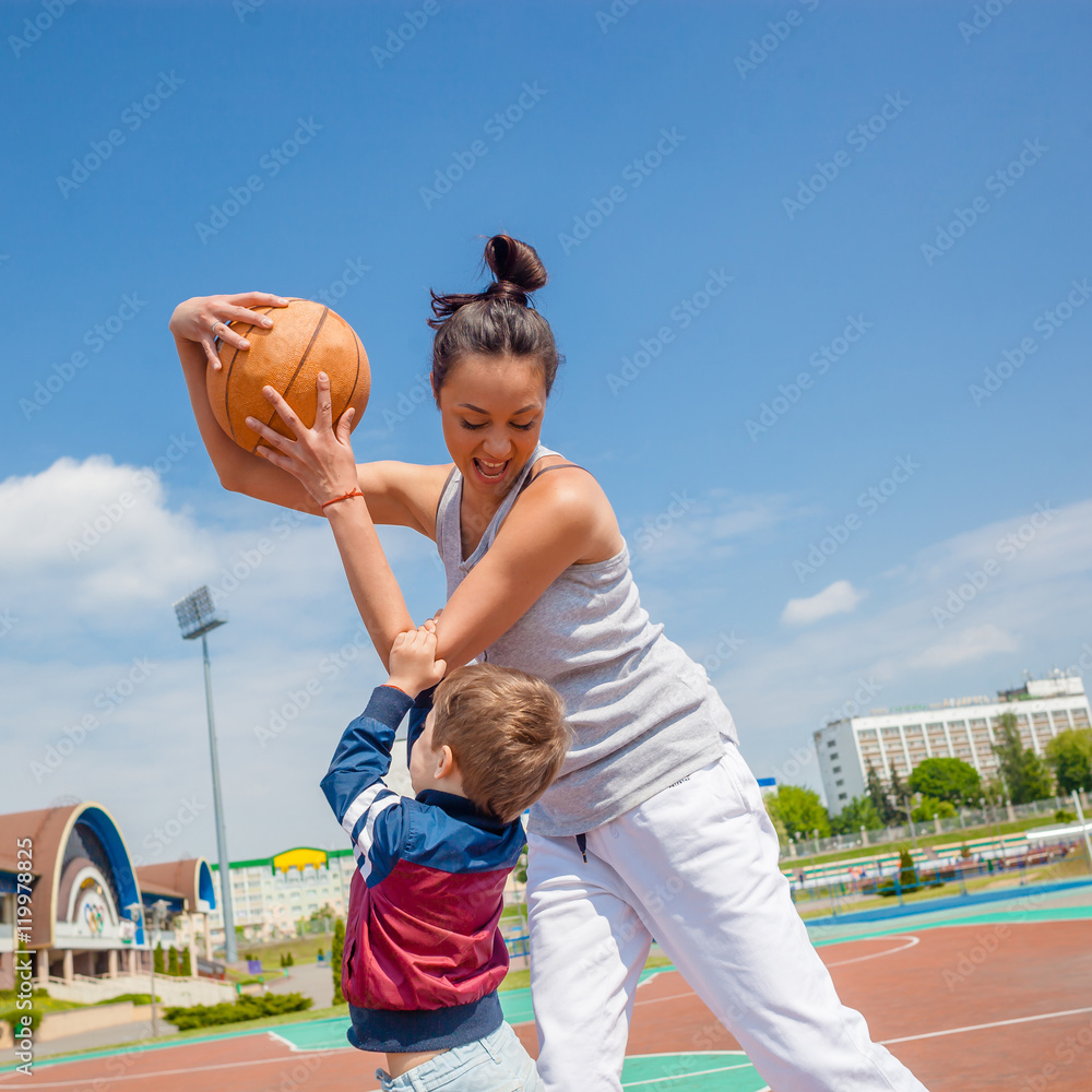 Fototapeta premium Mom and little boy son playing basketball
