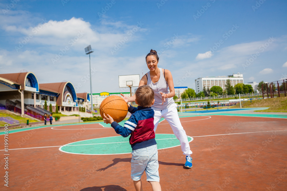 Mom and little boy son playing basketball