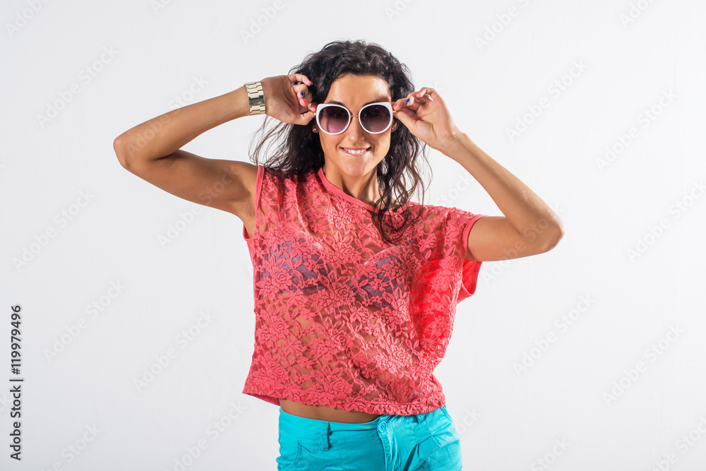 Studio portrait of a playful girl having fun, wearing sunglasses and trendy summer outfit. Studio portrait of a playful girl having fun, wearing sunglasses and trendy summer outfit.