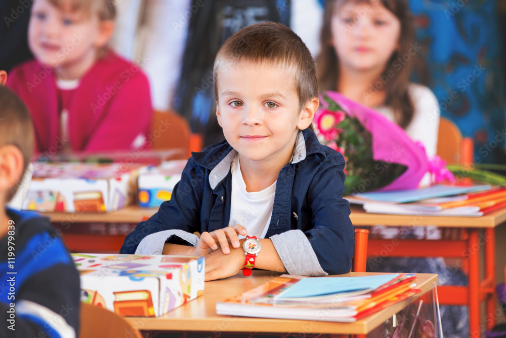 Young first grade student sitting at desk on his first day at sc Young first grade student sitting at desk on his first day at sc
