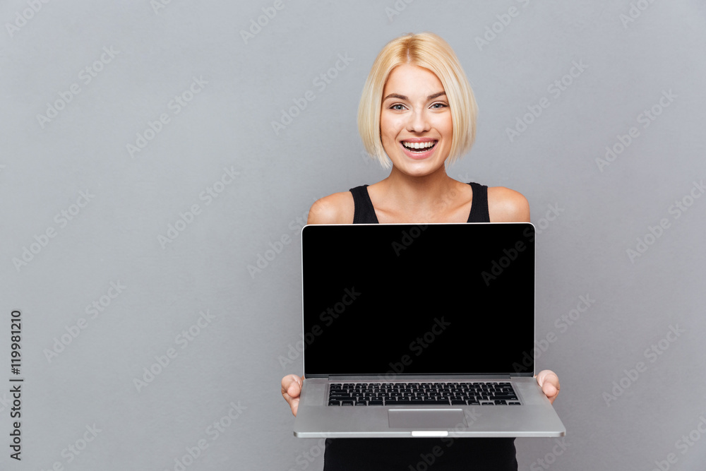 Happy cute young woman holding blank screen laptop Happy cute young woman holding blank screen laptop