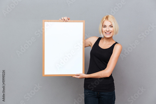 Happy pretty young woman holding blank white board