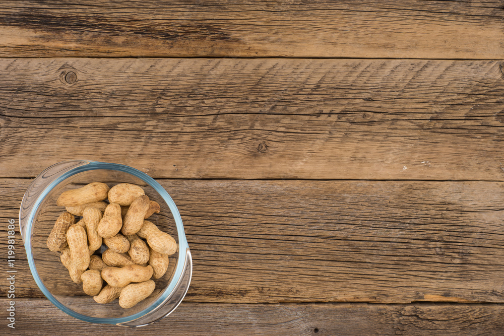 Peanuts in a glass bowl on the old wooden table. Peanuts in a glass bowl on the old wooden table.