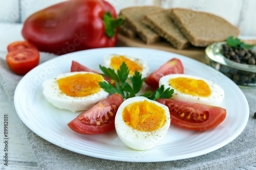 Boiled egg and fresh tomato, black bread - light diet breakfast. Close up