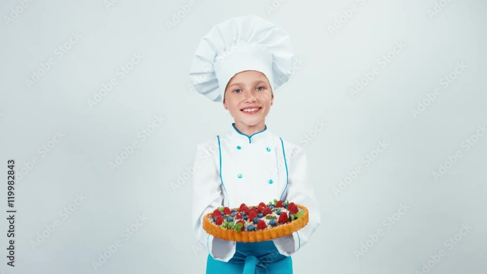 Close up portrait young baker holding in her hand chocolate cake with sweets and fruits sniffing it and smiling at camera with teeth. Isolated on white Close up portrait young baker holding in her hand chocolate cake with sweets and fruits sniffing it and smiling at camera with teeth. Isolated on white