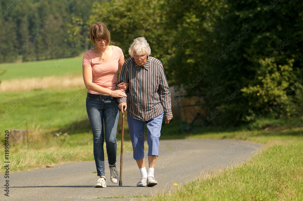 Junge Frau hilft Seniorin beim laufen