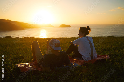 Hip young tourists enjoying the view of a beach and green hills during sunset