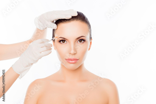 Plastic surgeon making botox injection in woman's eyebrow