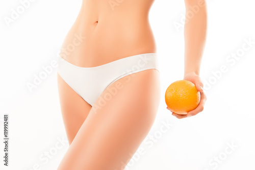 Close up of woman in white panties holding orange near hip