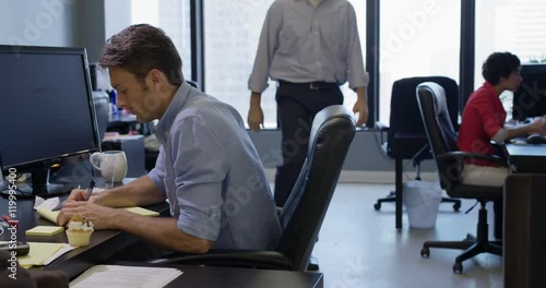 Business man engages co-worker in conversation and distracts him so he can steal cup cake from his desk.  Wide shot, recorded in real time in open-plan city office.