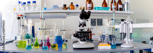 Tableau sur toile Laboratory table piled tubes with colored liquid, colored reagents in flasks and