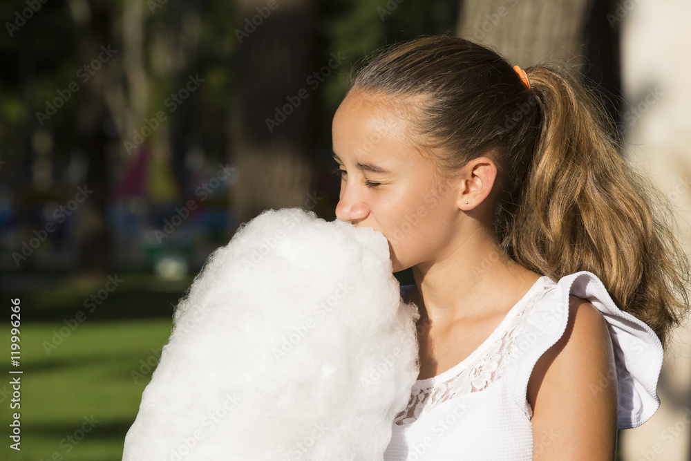 Girl eating cotton candy in a summer park Girl eating cotton candy in a summer park
