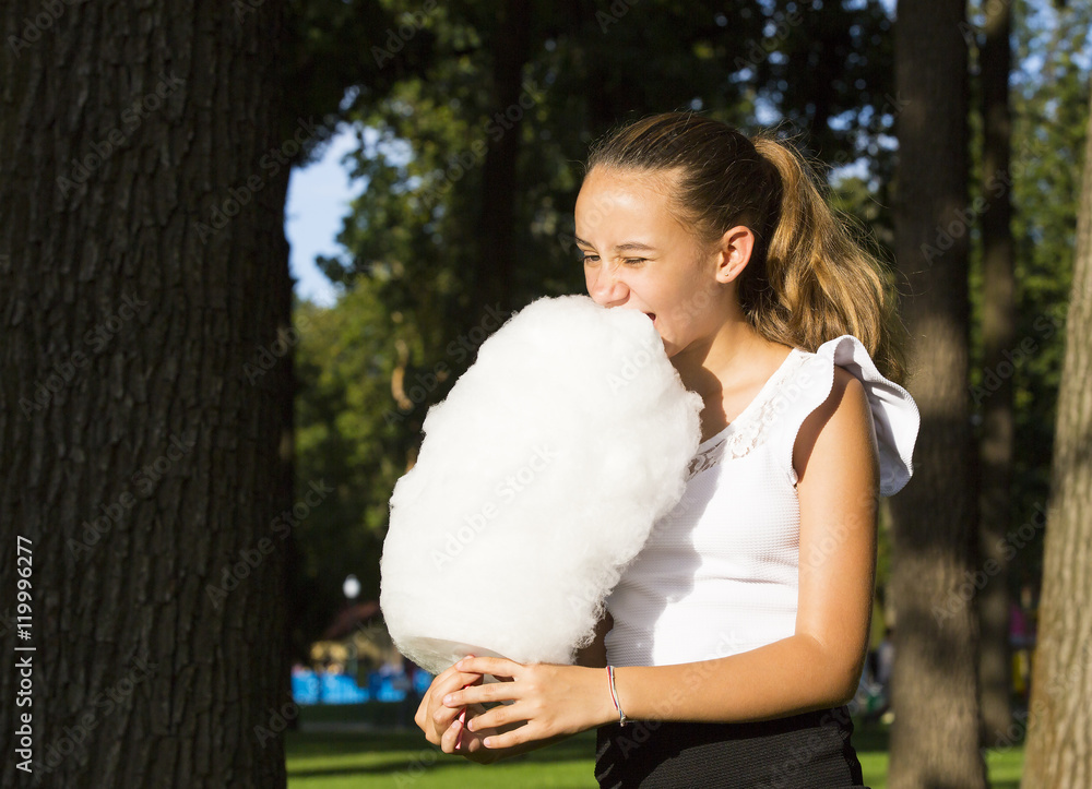Girl eating cotton candy in a summer park Girl eating cotton candy in a summer park