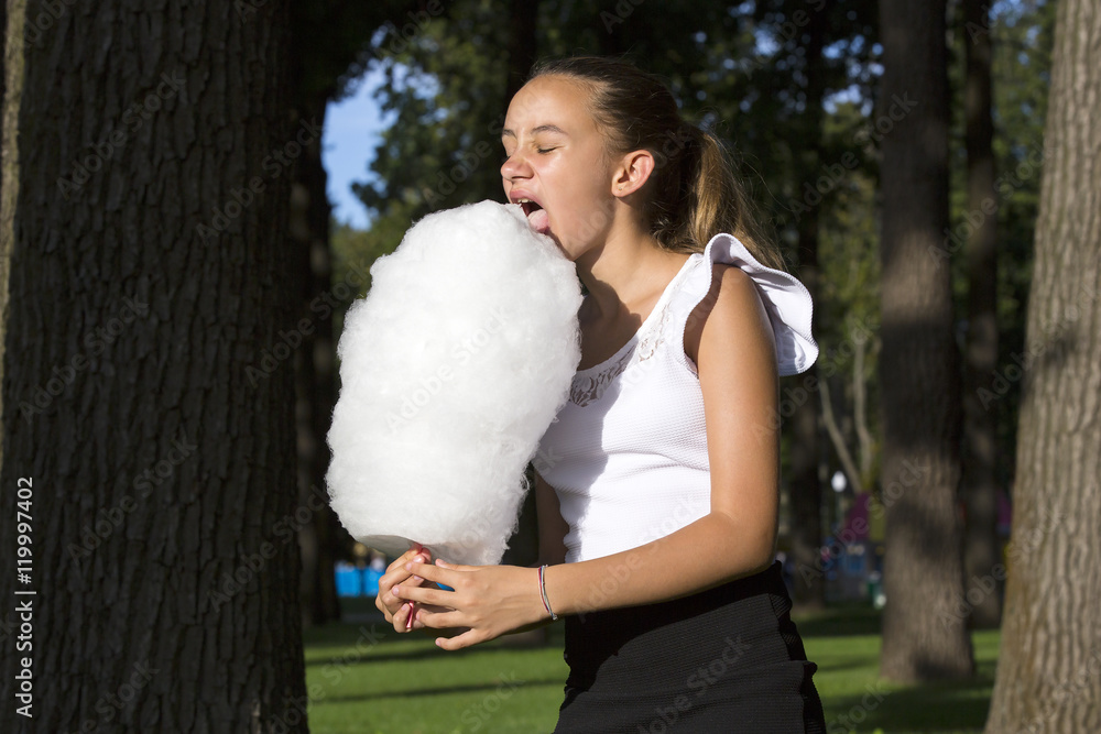 Girl eating cotton candy in a summer park Girl eating cotton candy in a summer park