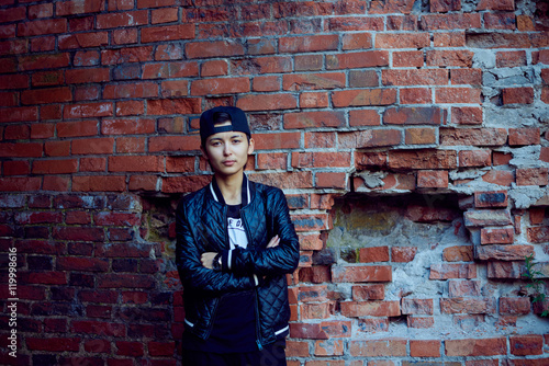 Asian girl on old red brick wall background. Woman in dark casua