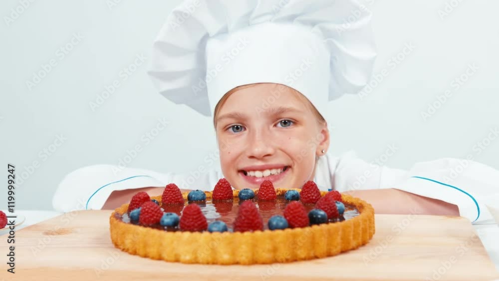 Close up portrait young baker looking at chocolate cake with fruits raspberries and blueberries isolated on white Close up portrait young baker looking at chocolate cake with fruits raspberries and blueberries isolated on white