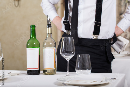 served table restaurant wine being poured into glass, white tablecloth, plates and cutlery