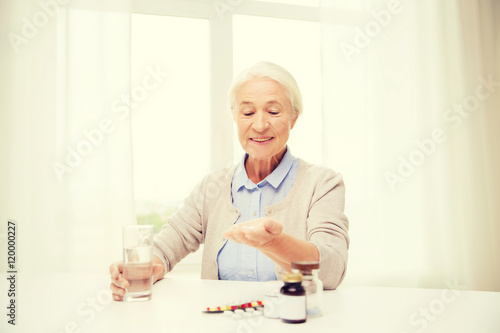 happy senior woman with water and medicine at home