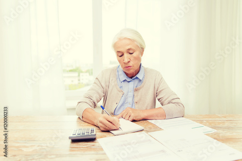 senior woman with papers and calculator at home