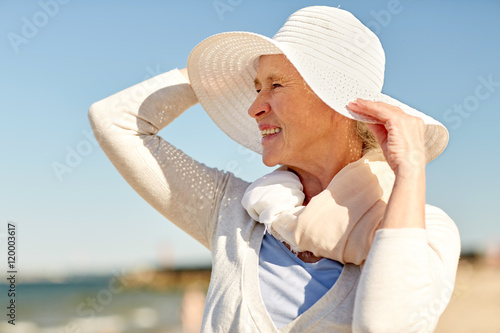 happy senior woman in sun hat on summer beach photo