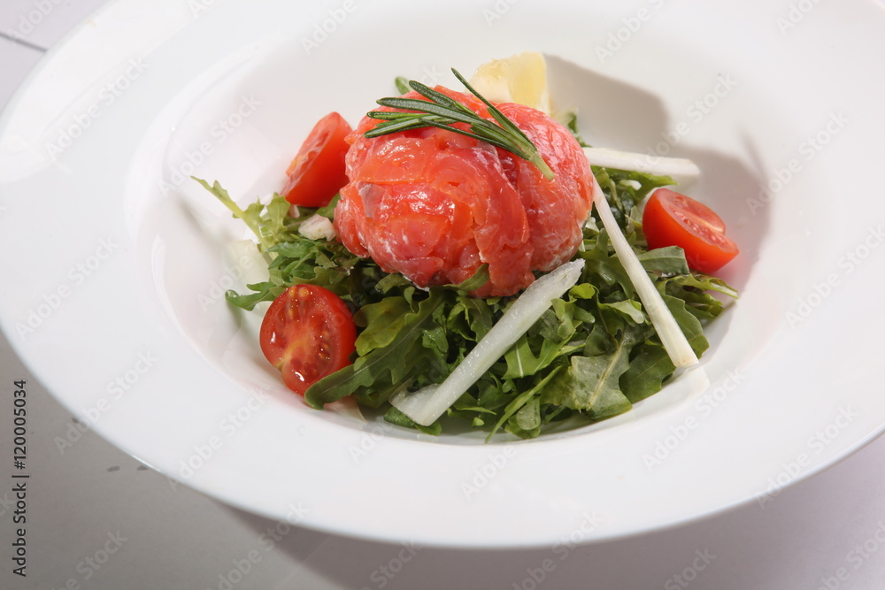 Red fish on Arugula in white plate Red fish on Arugula in white plate