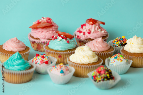 Closeup of tasty freshly baked cupcakes and colorful candies ove