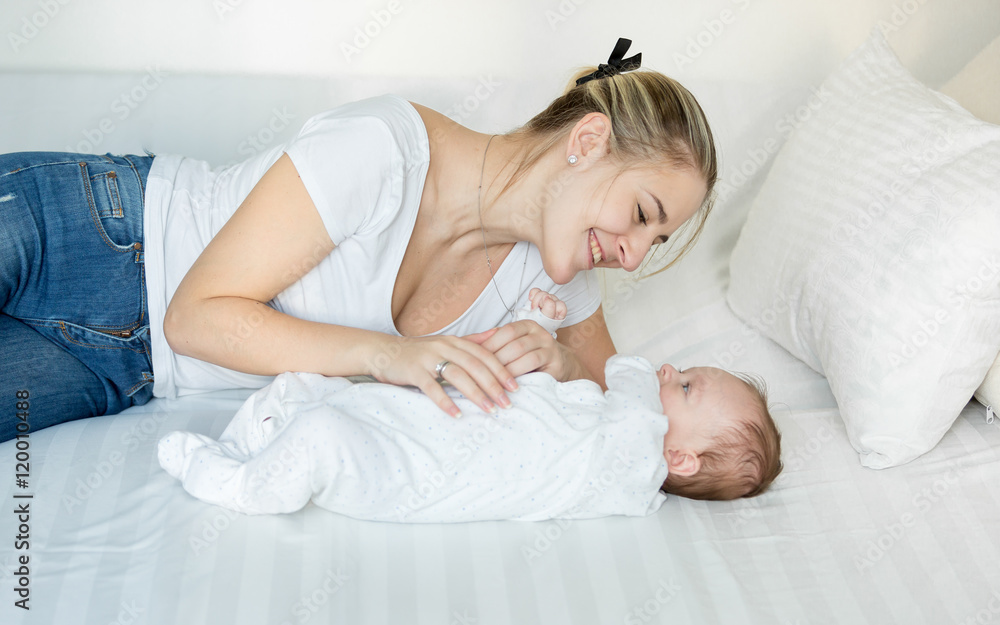 Smiling mother playing on bed with her cute baby boy Smiling mother playing on bed with her cute baby boy