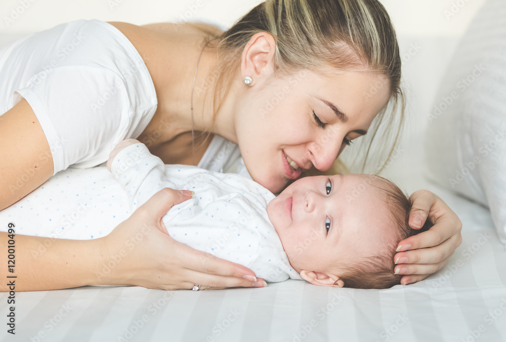 Closeup portrait of happy mother kissing her baby boy on bed Closeup portrait of happy mother kissing her baby boy on bed