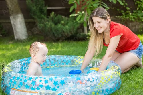 Mother and her baby boy playing in swimming pool at hot summer d