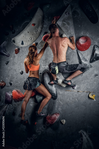 Male and female climbing on an indoor climbing wall.