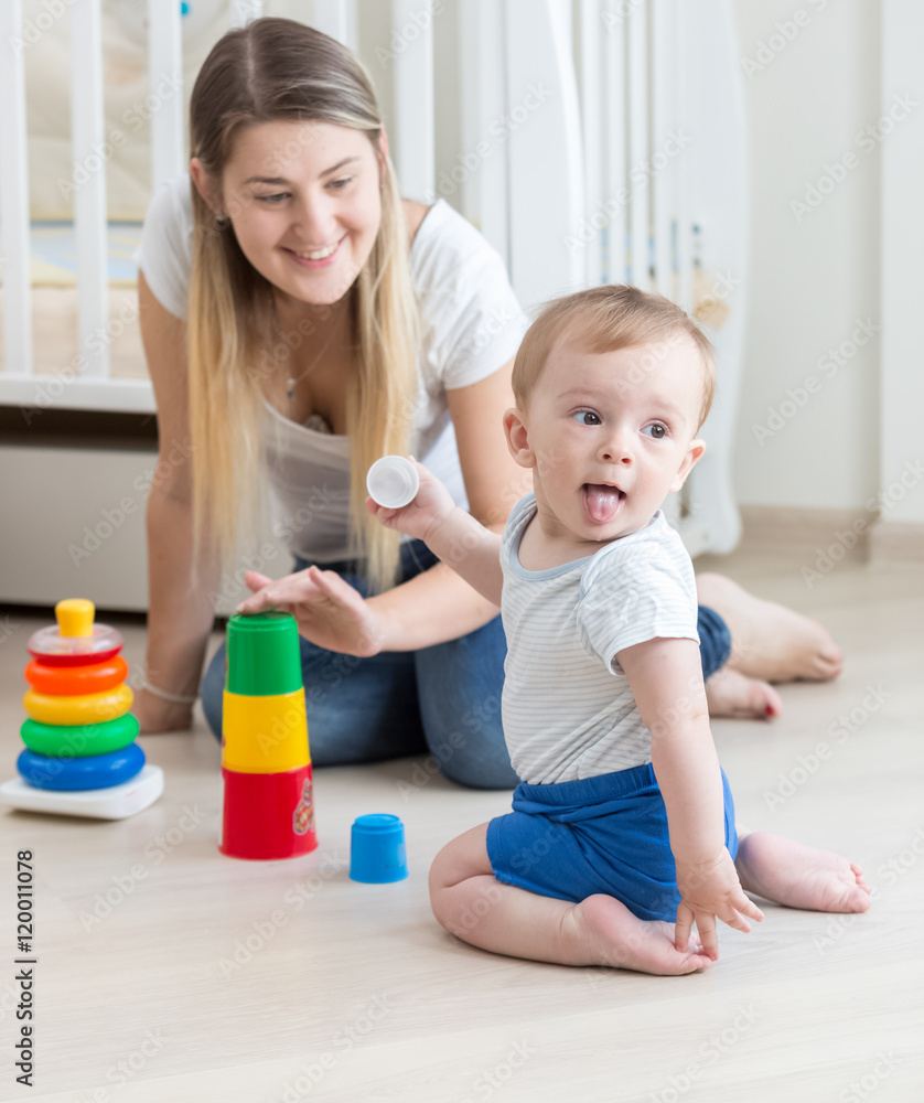 Smiling mother assembling toy pyramid with her baby boy Smiling mother assembling toy pyramid with her baby boy