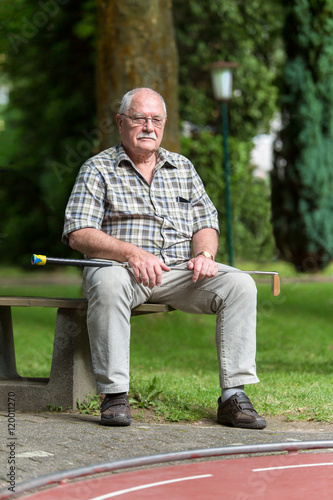 Ein Senior ruht sich während des Minigolfspiels auf einer Bank aus.
